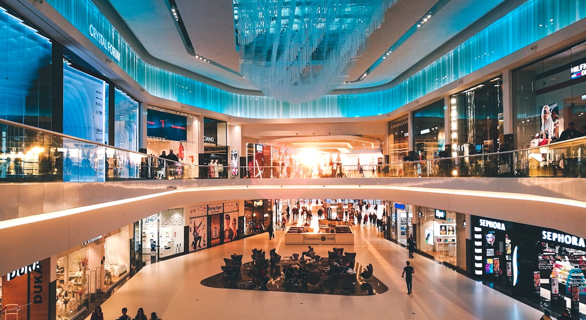 Multi-level shopping mall interior with escalators and shoppers